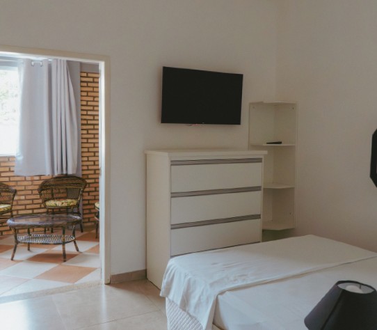 Quarto com TV, cômoda e sala de estar anexa