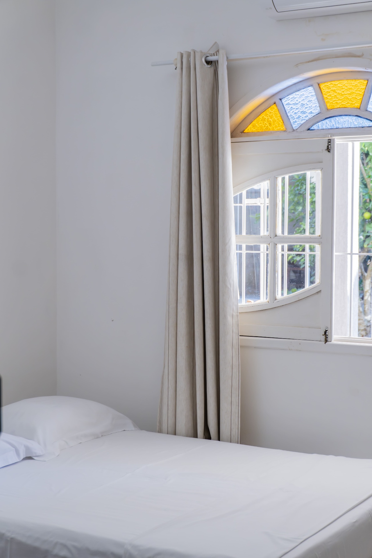 Quarto Cavalinha — cama e janela em arco com vitral