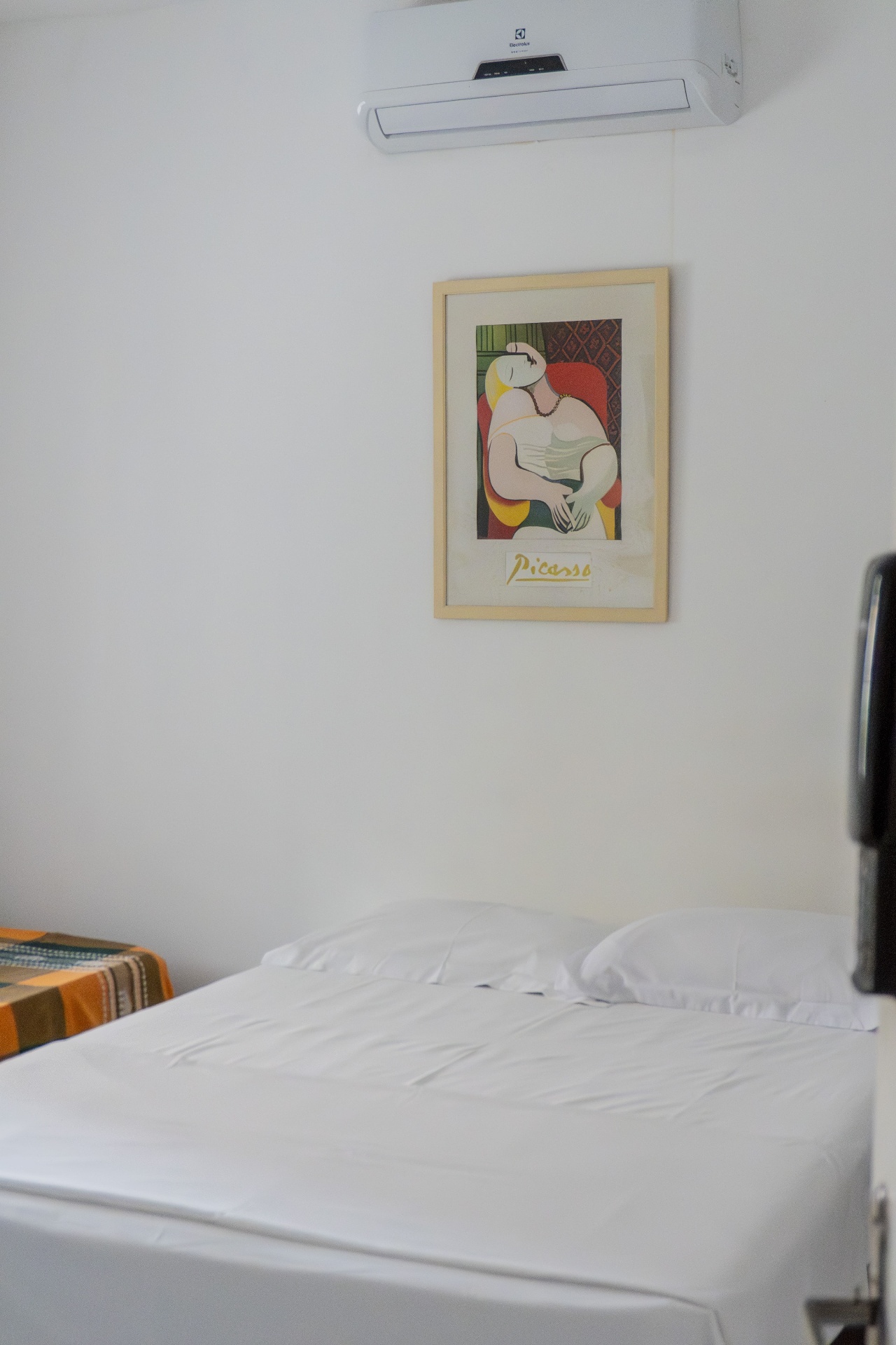 Quarto Manjubinha — detalhe da cama com ar-condicionado