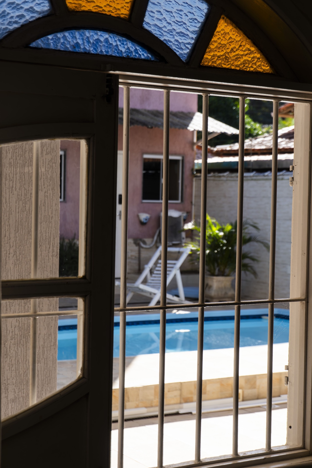 Quarto Cavalinha — janela em arco com vitral e vista da piscina