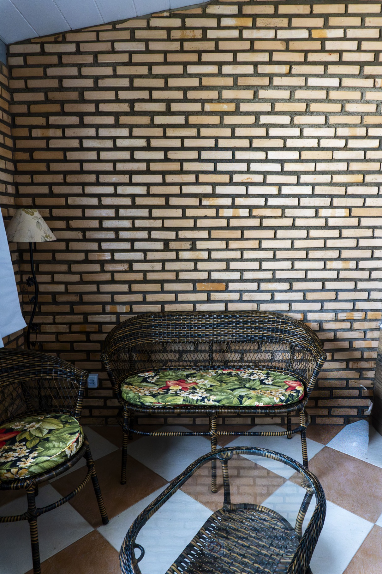 Quarto Tainha — sofá de vime com almofadas floridas
