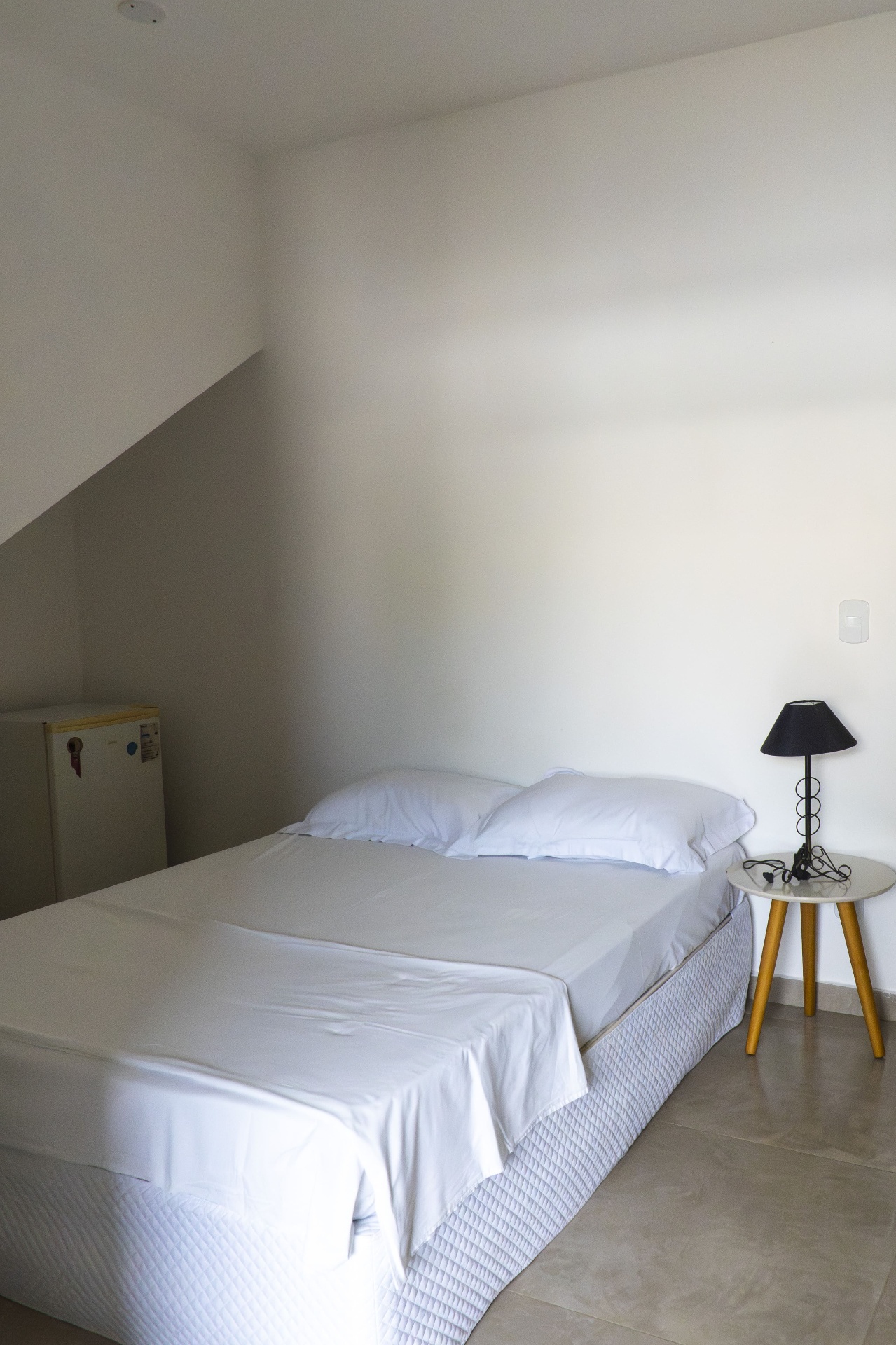 Quarto Tainha — cama de casal com frigobar ao fundo