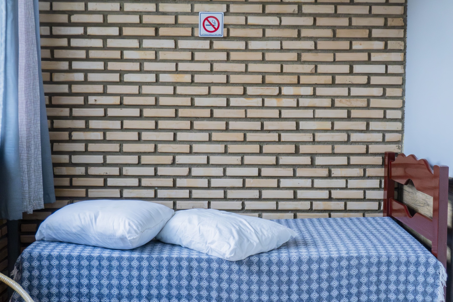 Quarto Sardinha — cama de casal com parede de tijolinhos