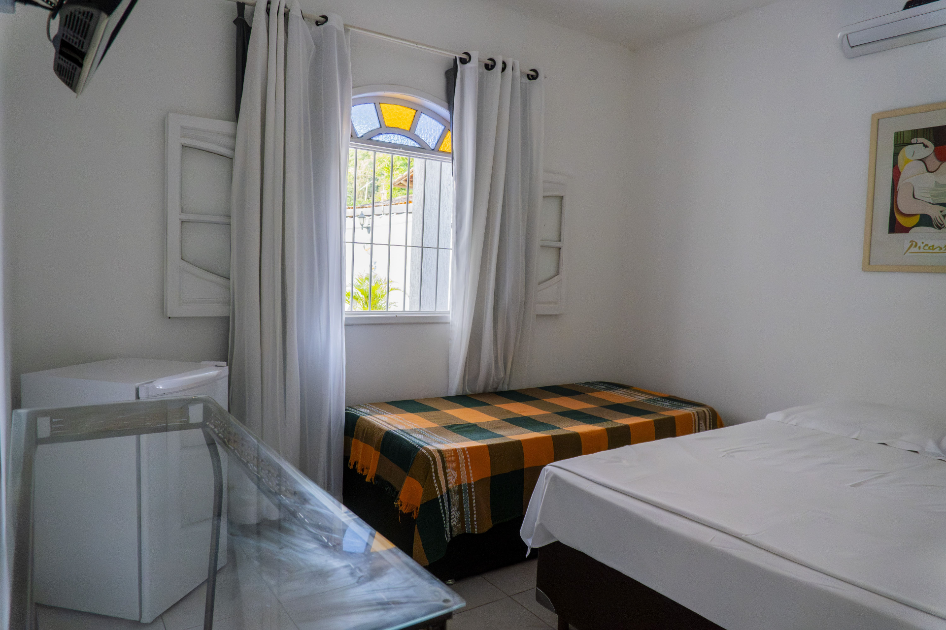 Quarto Manjubinha — janela em arco com vitral e frigobar