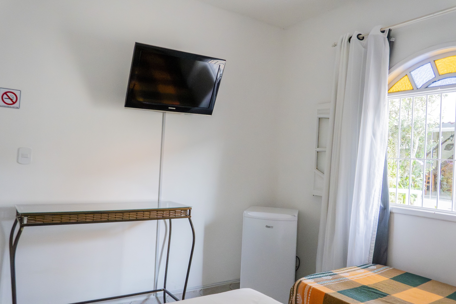 Quarto Manjubinha — TV, frigobar e janela com vitral